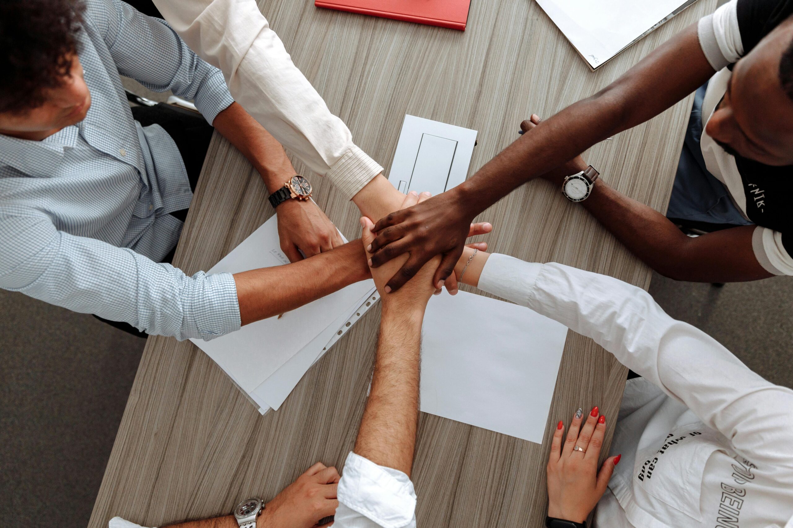 a diverse group of people putting their hands together above a table